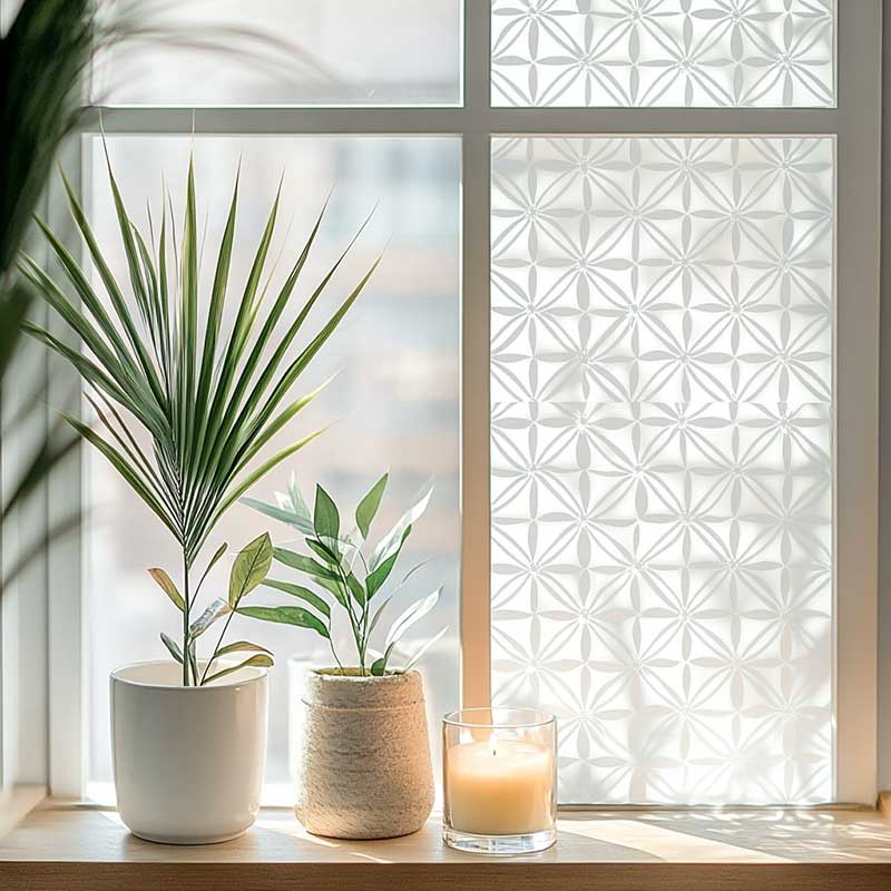 Decorative patterned glass enhanced by Home Window Film, with greenery and a candle on the sill 